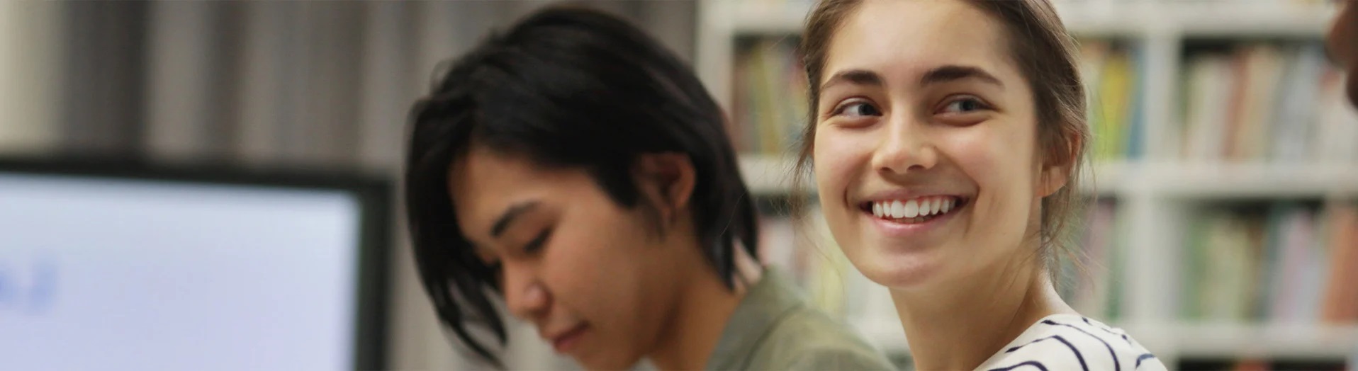 Smiling students in a library.
